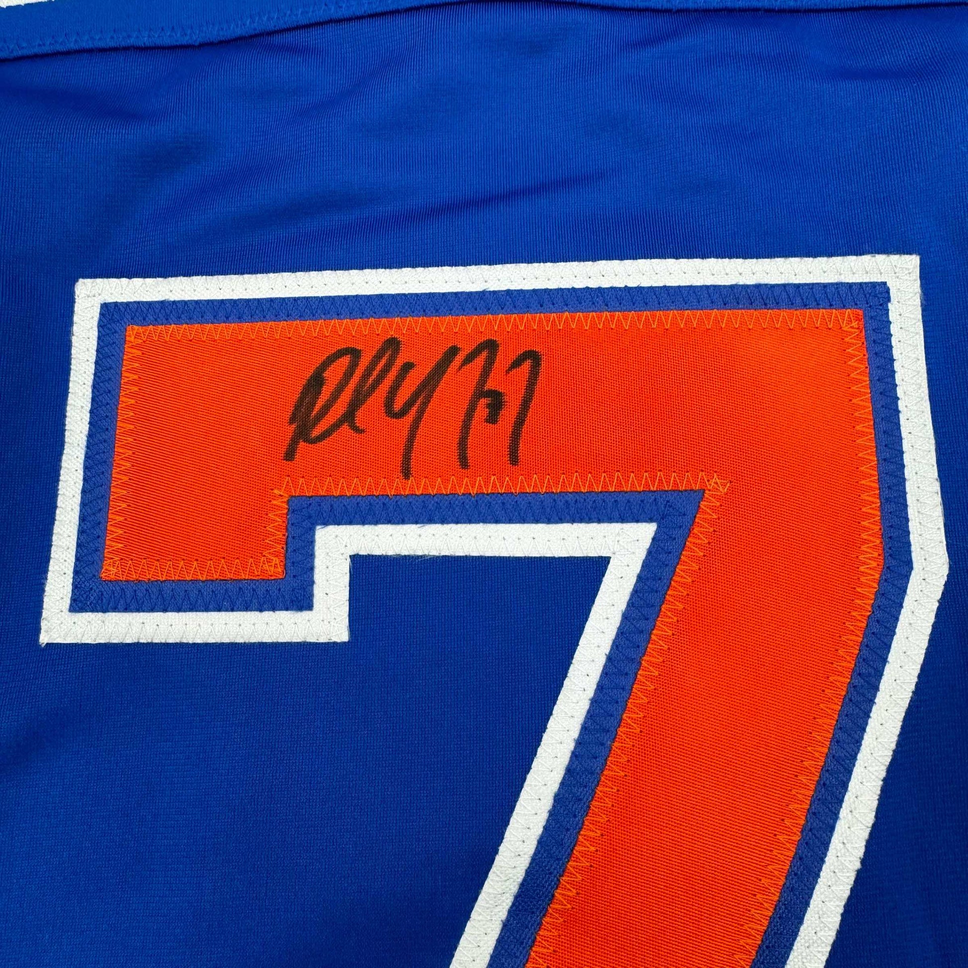 Close-up of autographed number 7 on blue and orange Edmonton Oilers hockey jersey with white trim.