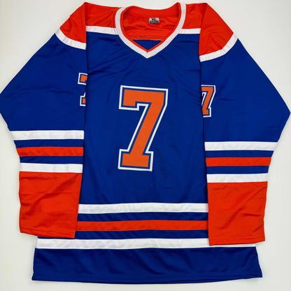 Blue Edmonton Oilers hockey jersey with orange number 7, red and white striping, displayed flat against white background.