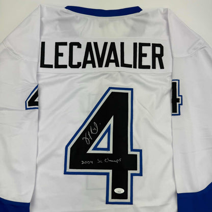 Back view of white hockey jersey with navy blue trim, displaying "LECAVALIER" across shoulders and large number 4, signed in black ink with "2004 SC Champs" notation.