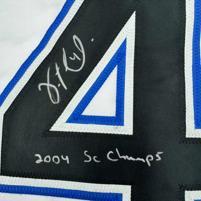 Close-up of autographed black jersey stripe showing handwritten signature and "2004 SC Champs" text with blue and white trim.