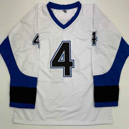 White hockey jersey with navy blue and black sleeves, large black number 4 with blue outline on chest, displayed flat against neutral background.