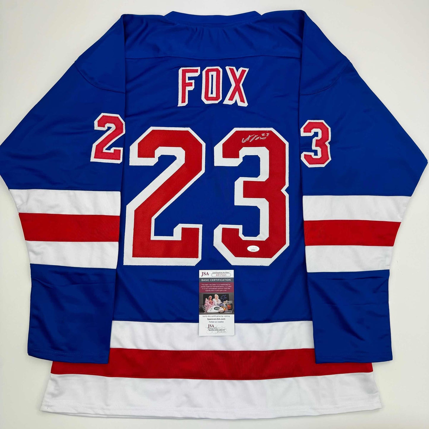 Back view of blue, white, and red striped hockey jersey with FOX and number 23 in red and white, featuring JSA authentication certificate.