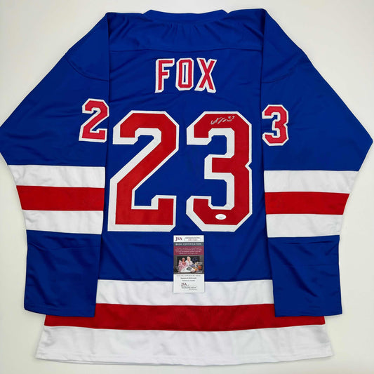 Back view of blue, white, and red striped hockey jersey with FOX and number 23 in red and white, featuring JSA authentication certificate.
