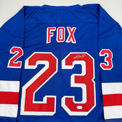 Back view of blue FOX hockey jersey with red and white number 23, signed across the chest.