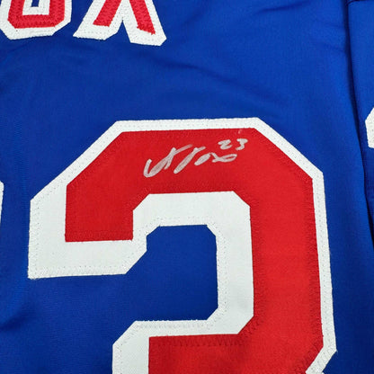 Close-up of red number 23 with autographed signature on blue hockey jersey with white trim.
