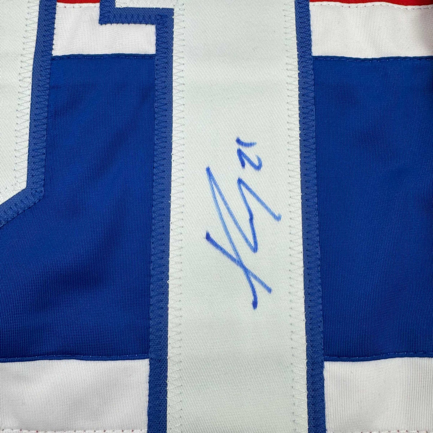 Close-up of blue pen autograph on white stripe of blue and white hockey jersey.