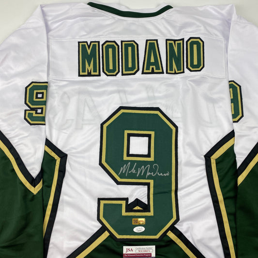 Close-up reverse view of a white jersey showing MODANO across the upper back and a signed green number 9.
