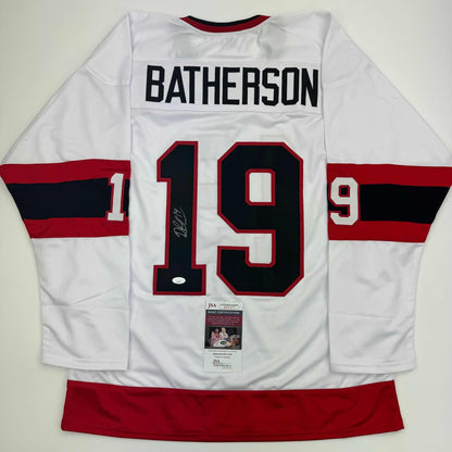 Back view of white hockey jersey with red and black striped sleeves, number 19, "BATHERSON" nameplate, and JSA authentication certificate visible.