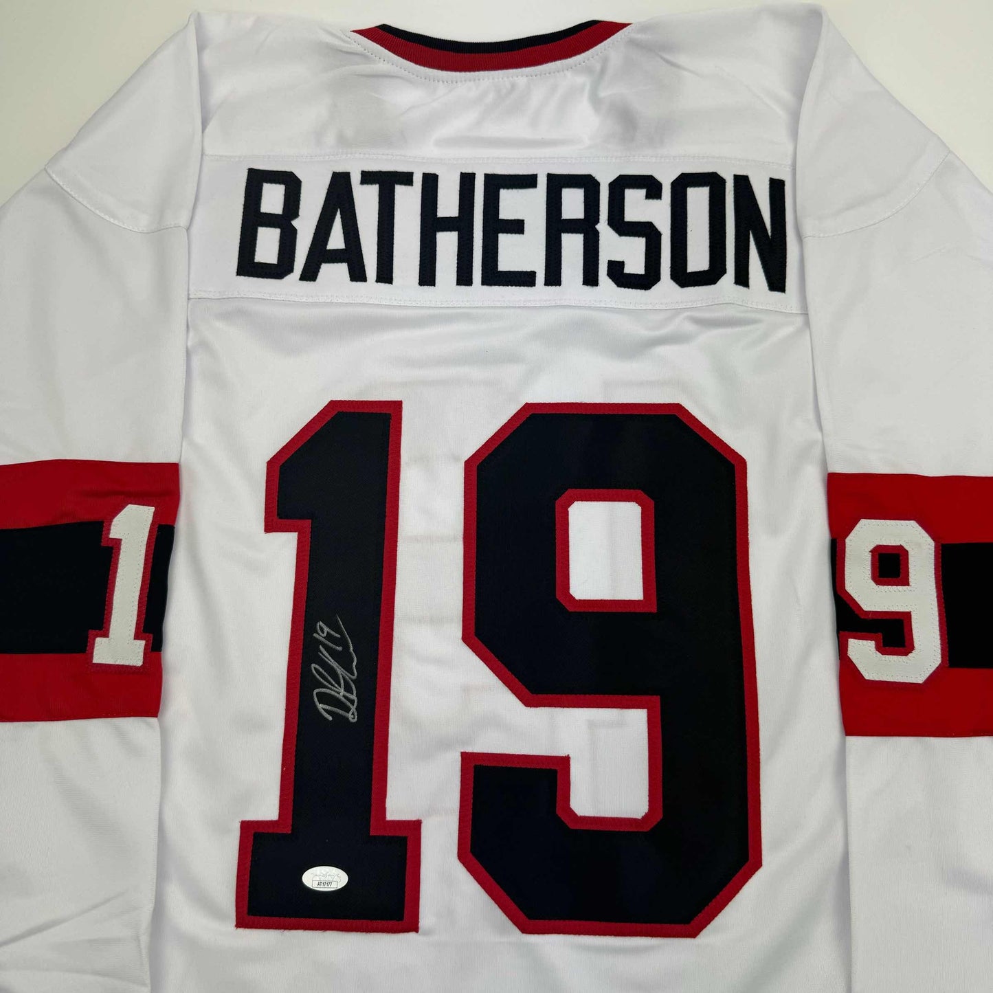 White hockey jersey with "BATHERSON" printed across shoulders and number 19 with autograph visible on front.
