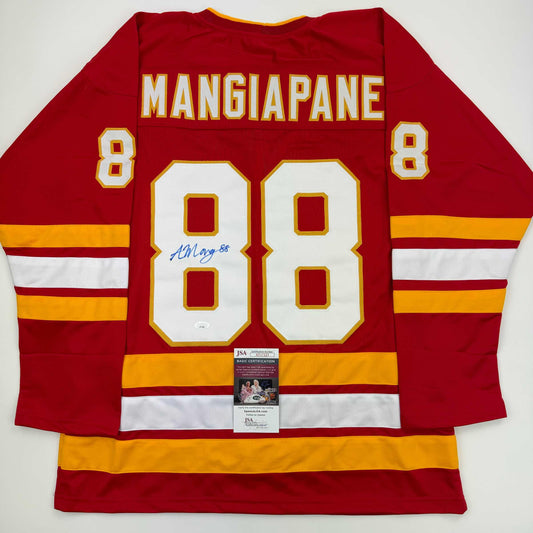 Flat lay of red Calgary Flames hockey jersey number 88 with "MANGIAPANE" nameplate, signed in blue ink, displaying JSA authentication certificate.