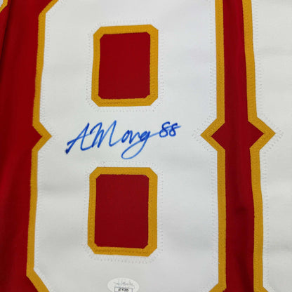 Close-up of white hockey jersey front panel with red and gold trim showing blue autograph "ALMangiapane 88" and JSA authentication label.