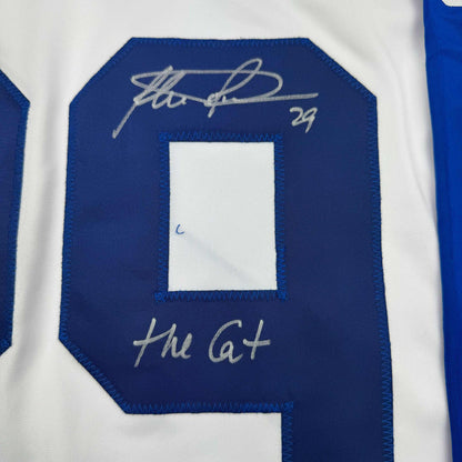Close-up of blue hockey jersey back showing signed autograph and "Hit a+" text above white rectangular patch.