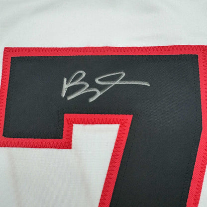 Close-up of autographed Brady Tkachuk jersey showing white signature on dark fabric with red and white trim.