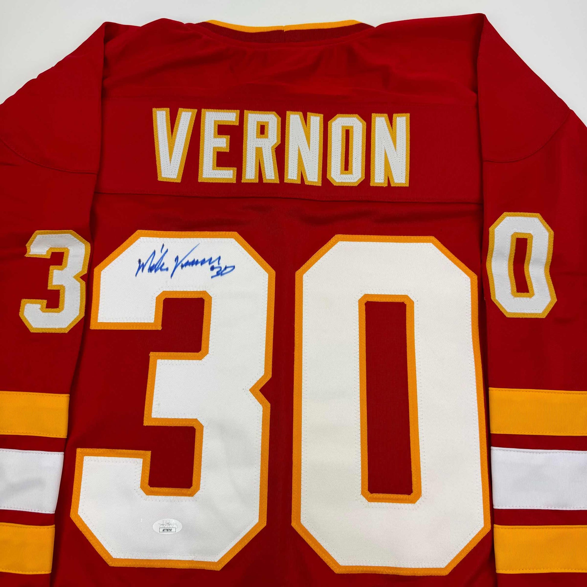 Red Calgary Flames hockey jersey with "VERNON" and number "30" displayed, featuring an autographed signature on the chest.