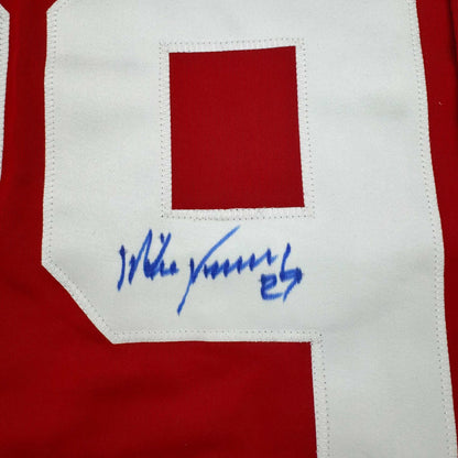 Close-up of signed red and white hockey jersey patch with blue handwritten signature reading "Mike Vernon" and number "27".
