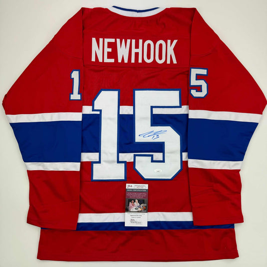 Red, white, and blue Montreal Canadiens hockey jersey displayed flat, showing back with "NEWHOOK" and number 15, signed in blue ink, with JSA authentication certificate attached.