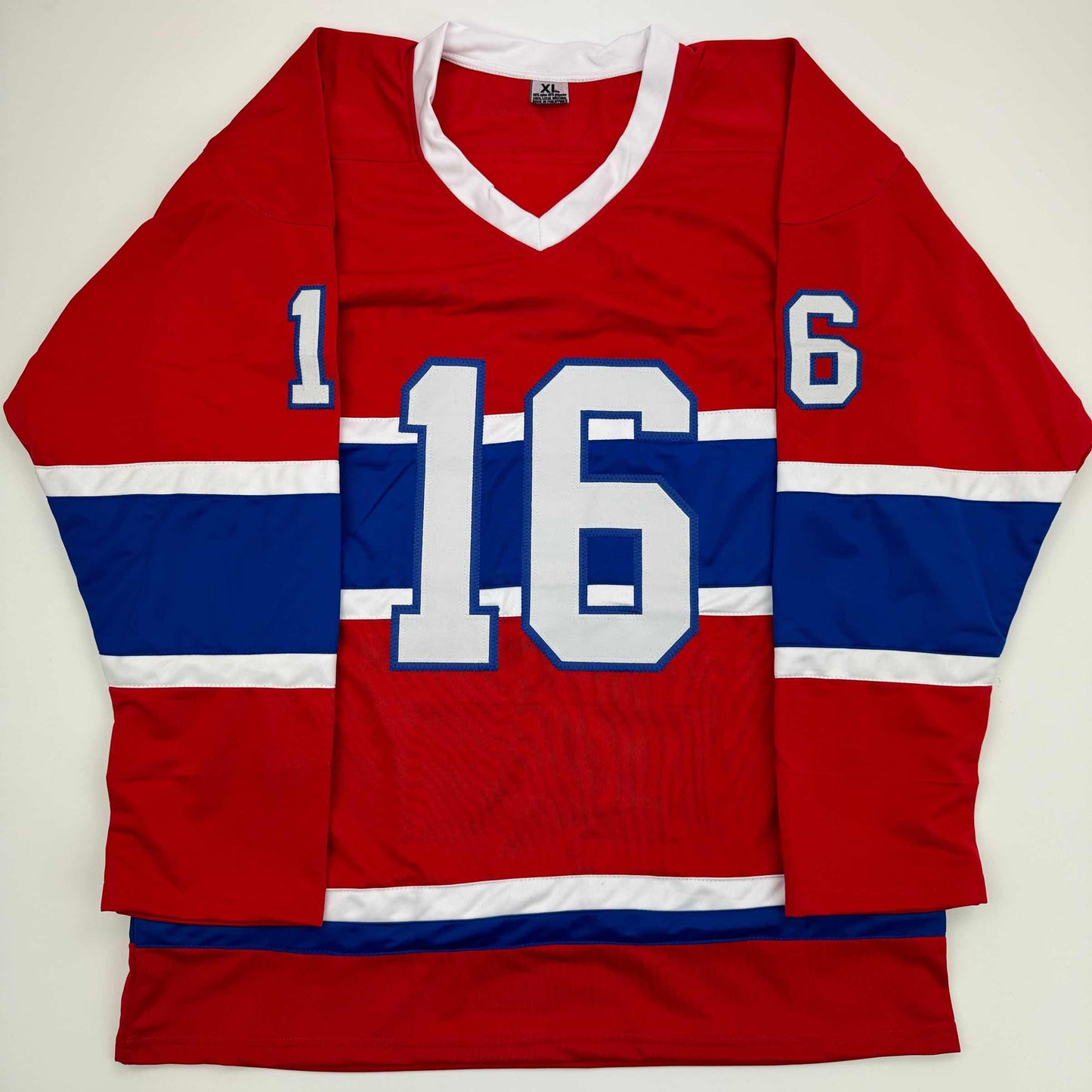 Red, white, and navy Montreal Canadiens hockey jersey with number 16 displayed flat against white background.