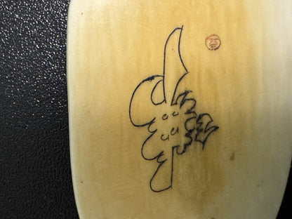Carved ox horn pendant with Chinese calligraphy inscribed vertically, shown against textured surface with penny placed upper right for scale reference.