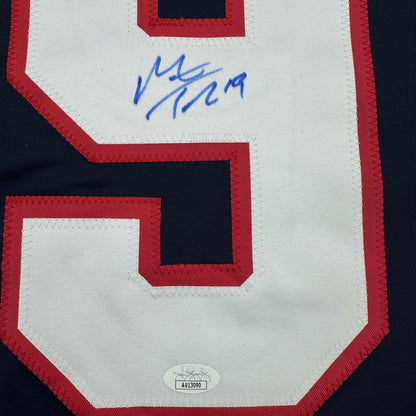 Close-up of red and white hockey jersey back showing blue autograph and JSA authentication label at bottom.