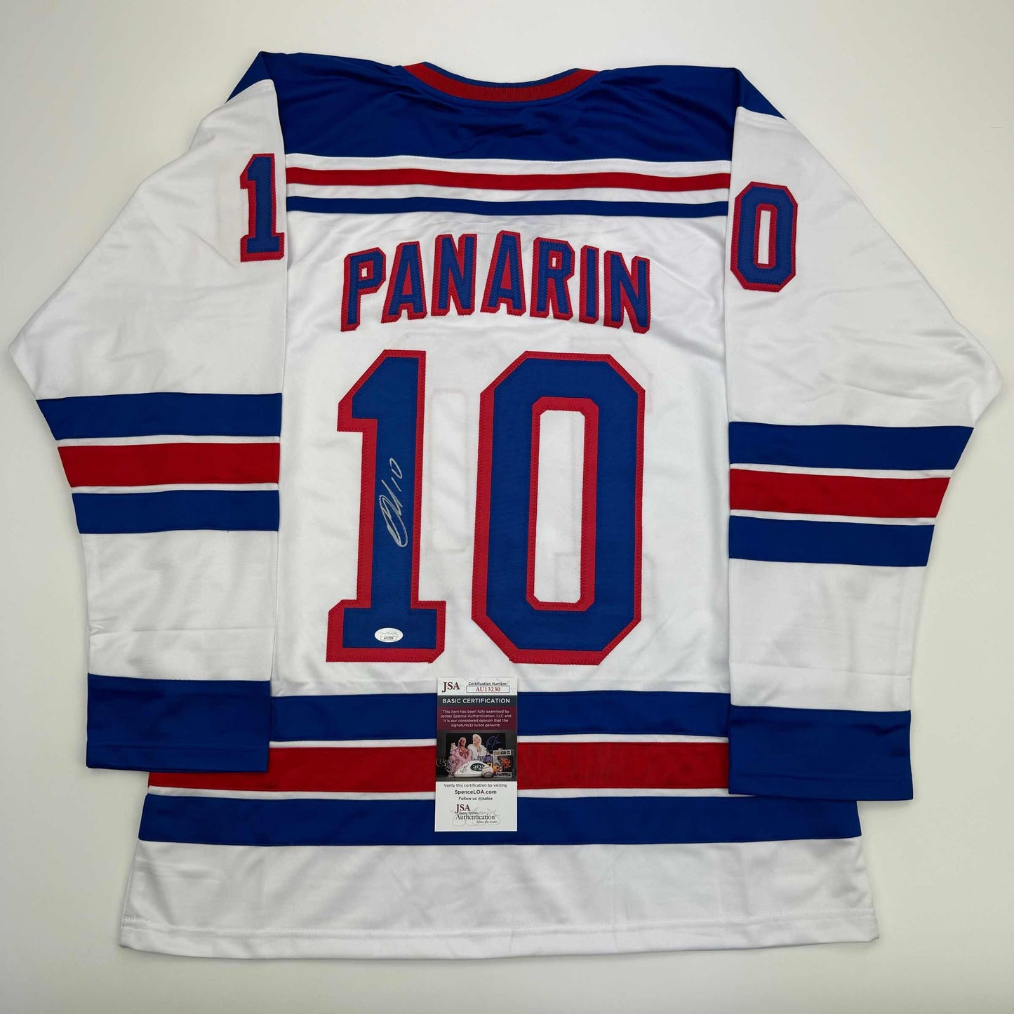 White hockey jersey with navy and red horizontal stripes displaying "PANARIN" and number 10, with JSA authentication certificate attached.