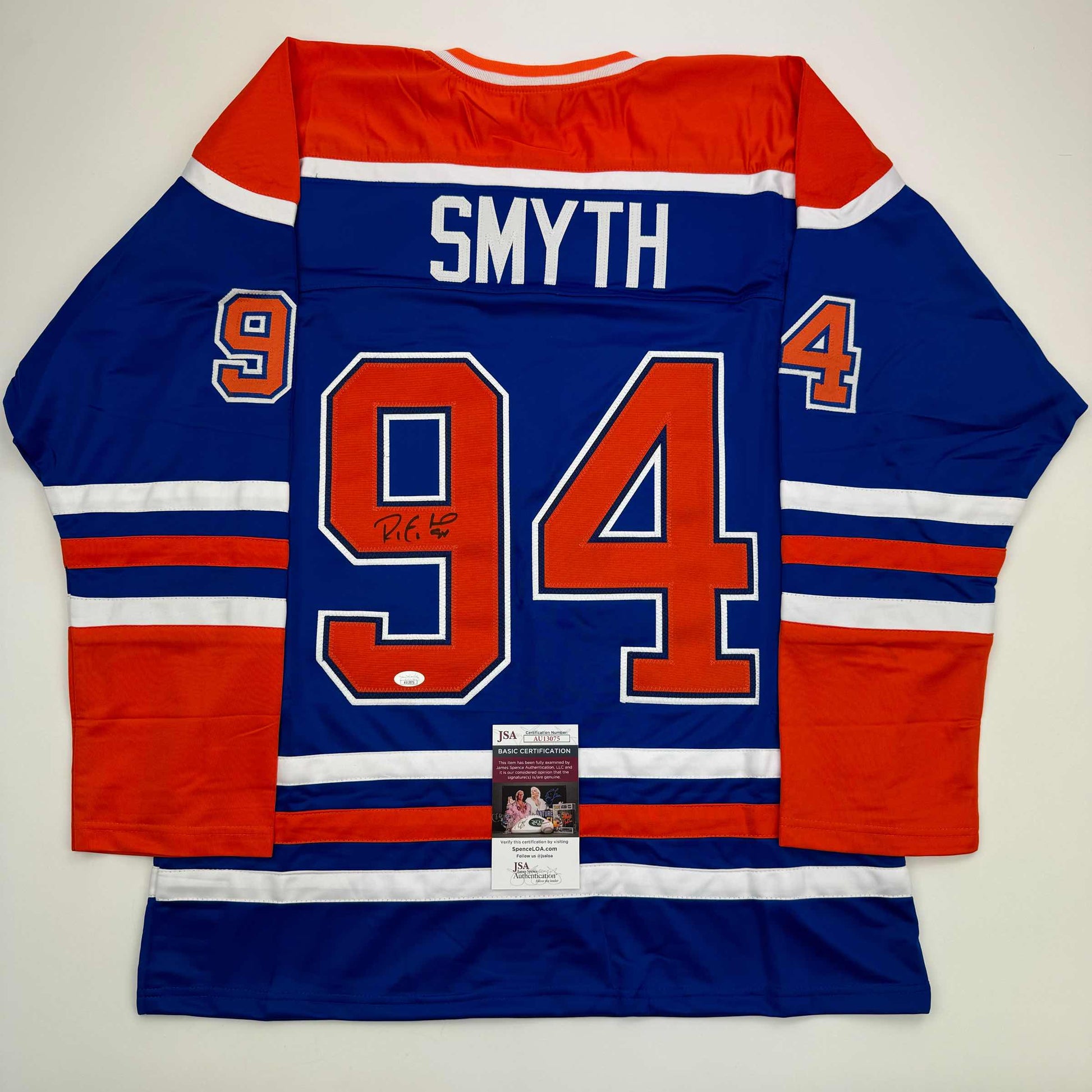 Blue Edmonton Oilers hockey jersey with red and white stripes, displaying "SMYTH" and number 94, with JSA authentication certificate visible at bottom center.