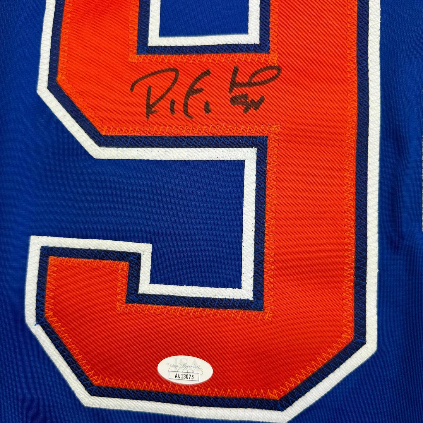 Close-up of signed Edmonton Oilers hockey jersey showing red and blue panel with handwritten signature and JSA authentication sticker.