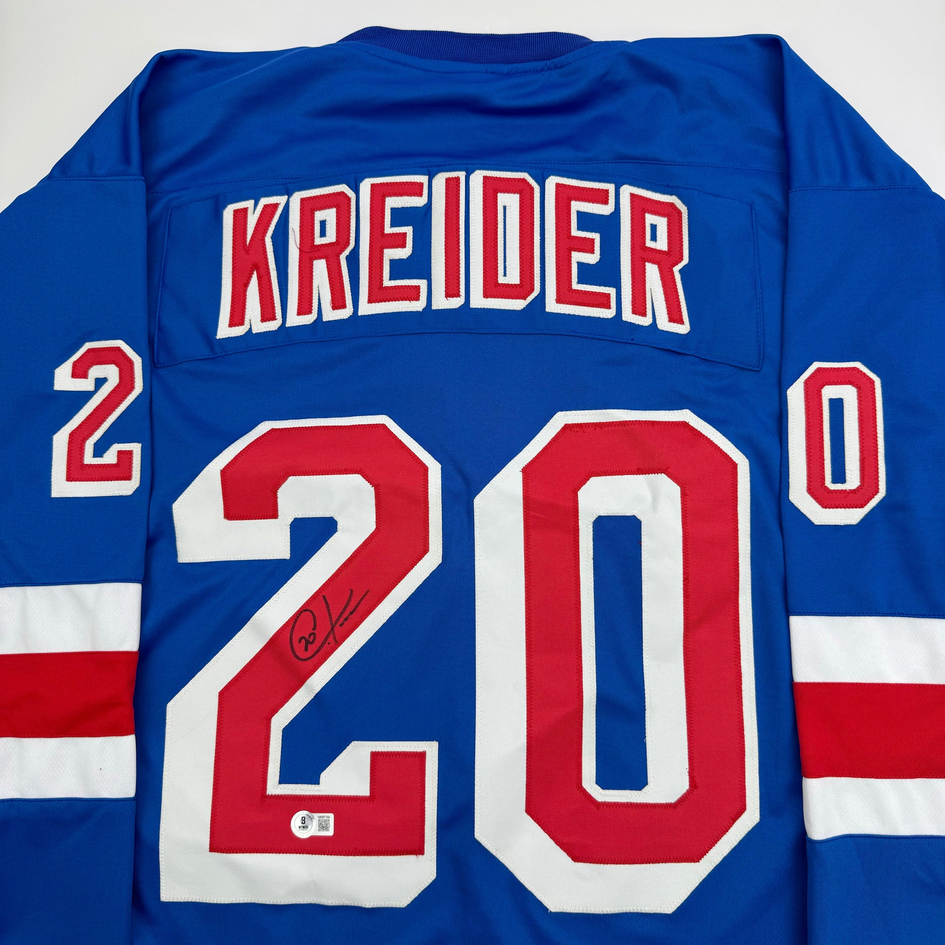 Blue New York Rangers hockey jersey with "KREIDER" and number 20 displayed on back, featuring red and white stripes, with visible autograph on the number.