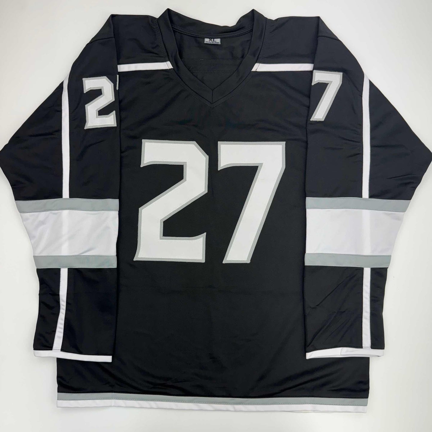 Black Los Angeles Kings hockey jersey number 27 displayed flat, showing front chest and sleeve numbering with white and gray striping.