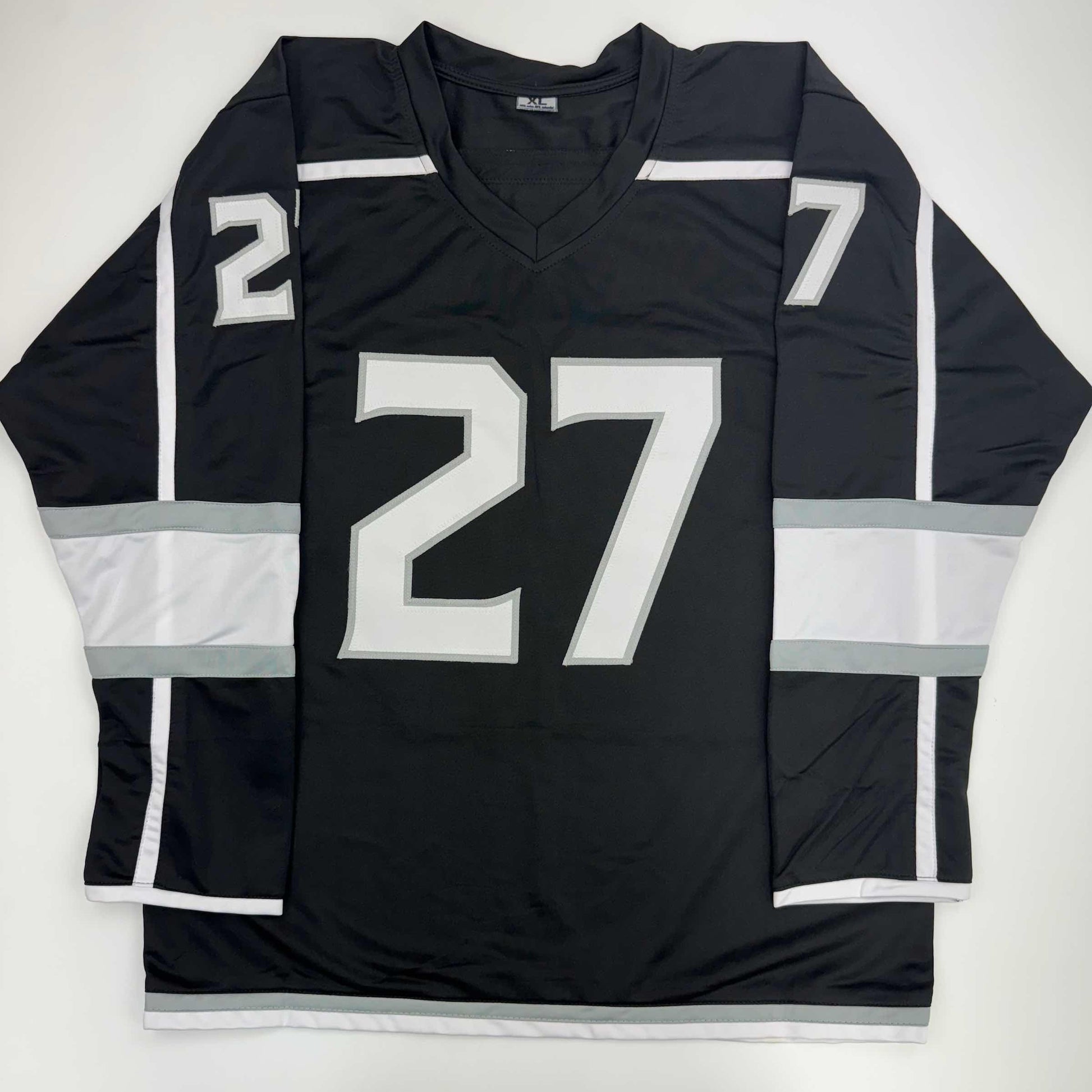 Black Los Angeles Kings hockey jersey number 27 displayed flat, showing front chest and sleeve numbering with white and gray striping.