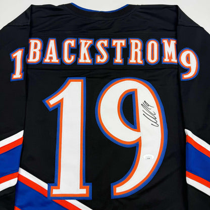 Back view of black hockey jersey with "BACKSTROM" and number 19 in orange and blue, featuring autographed signature on the number.