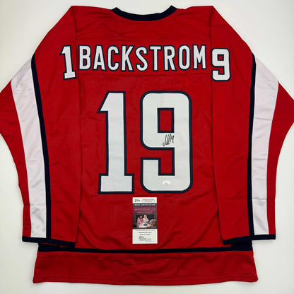 Red Washington hockey jersey number 19 with "Backstrom" nameplate, white stripes, signed with JSA authentication certificate visible.