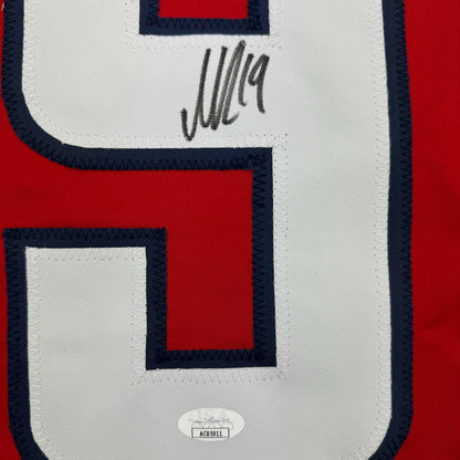 Close-up of white jersey panel with dark blue and red geometric design, handwritten signature, and JSA authentication sticker.