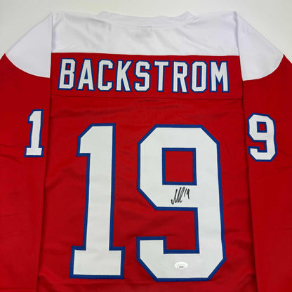 Red hockey jersey with white shoulders displaying "BACKSTROM" and number 19, front view with autographed number 19.