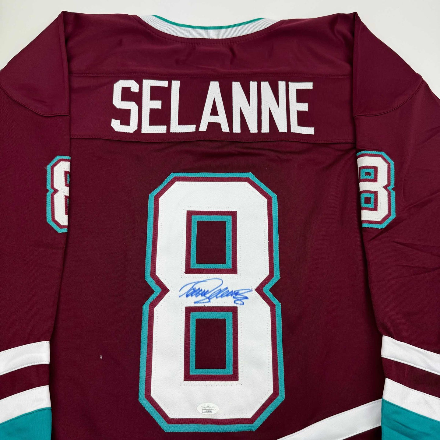 Back view of maroon hockey jersey with "SELANNE" and number 8 in white and turquoise, featuring a signature on the number.
