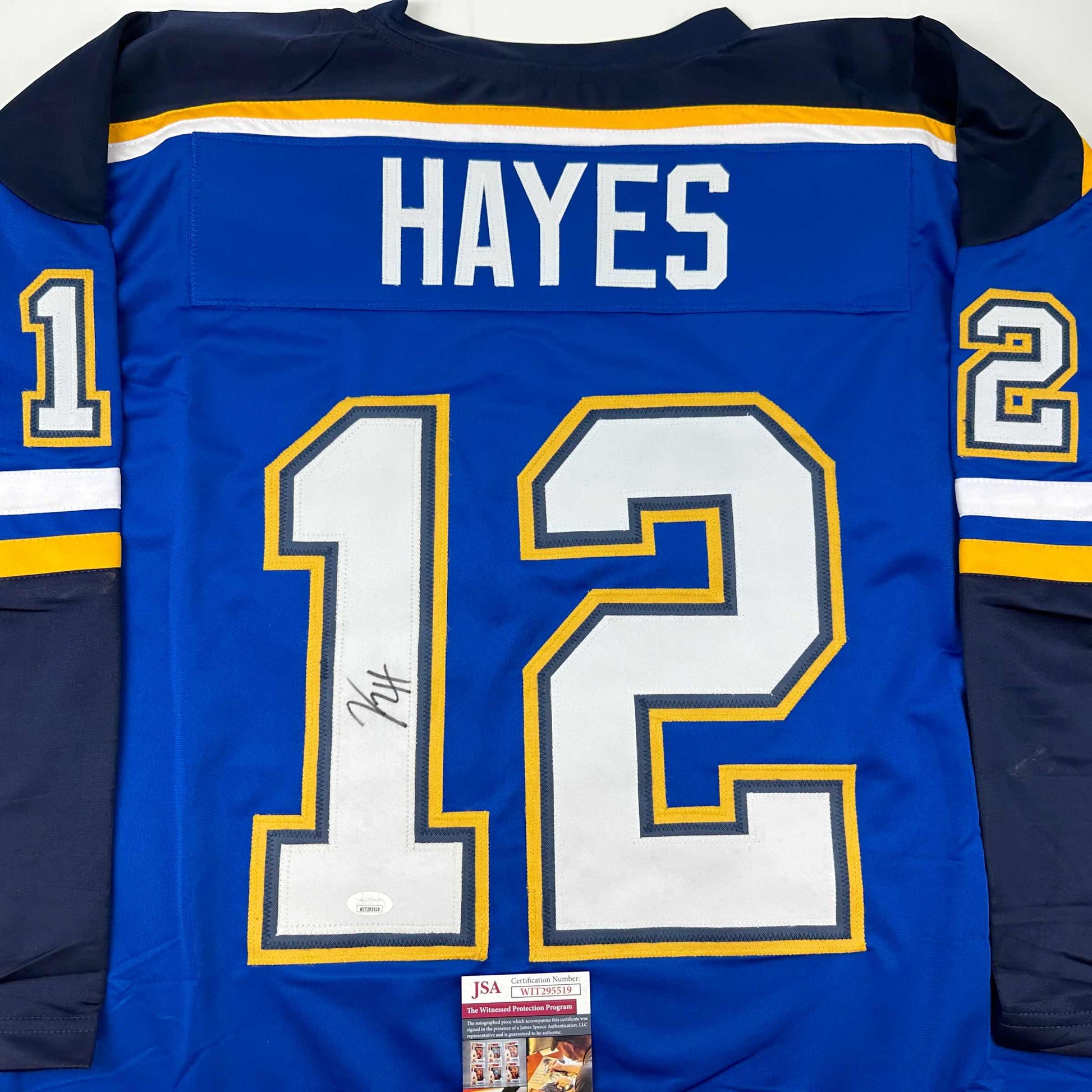 Back view of blue hockey jersey numbered 12 with "HAYES" nameplate and autograph, showing JSA authentication label.
