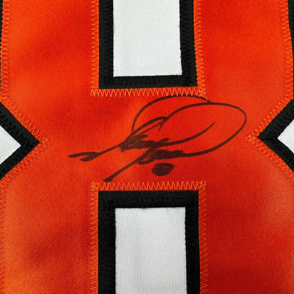 Close-up of red hockey jersey back showing black handwritten signature across center chest area with black and white trim details.
