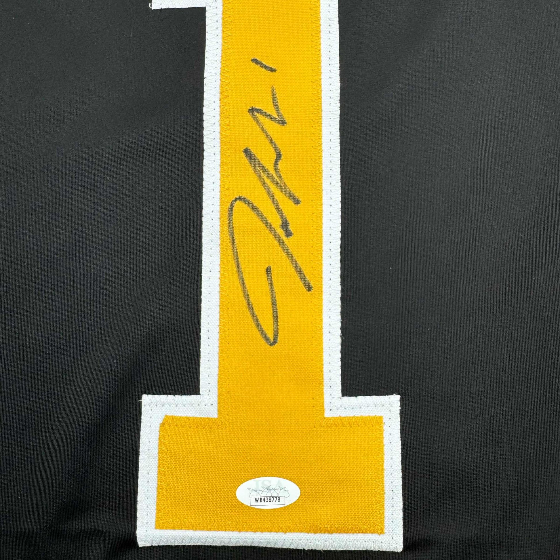 Close-up of yellow stripe with handwritten signature and JSA authentication label on black jersey fabric.
