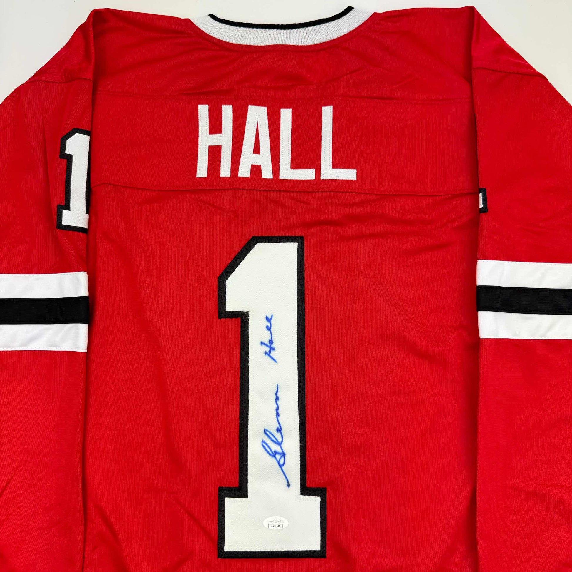Red hockey jersey back view displaying "HALL" and number "1" with blue autograph on the jersey front.