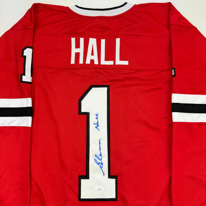 Red hockey jersey back view displaying "HALL" and number "1" with blue autograph on the jersey front.