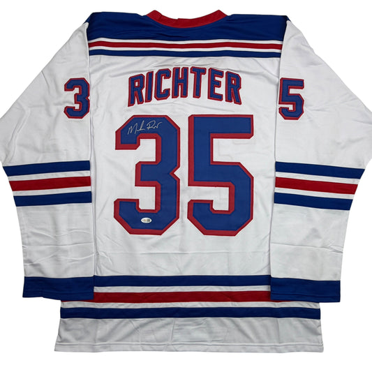 Back view of white hockey jersey with blue and red stripes, number 35, "RICHTER" nameplate, and autographed signature on chest.
