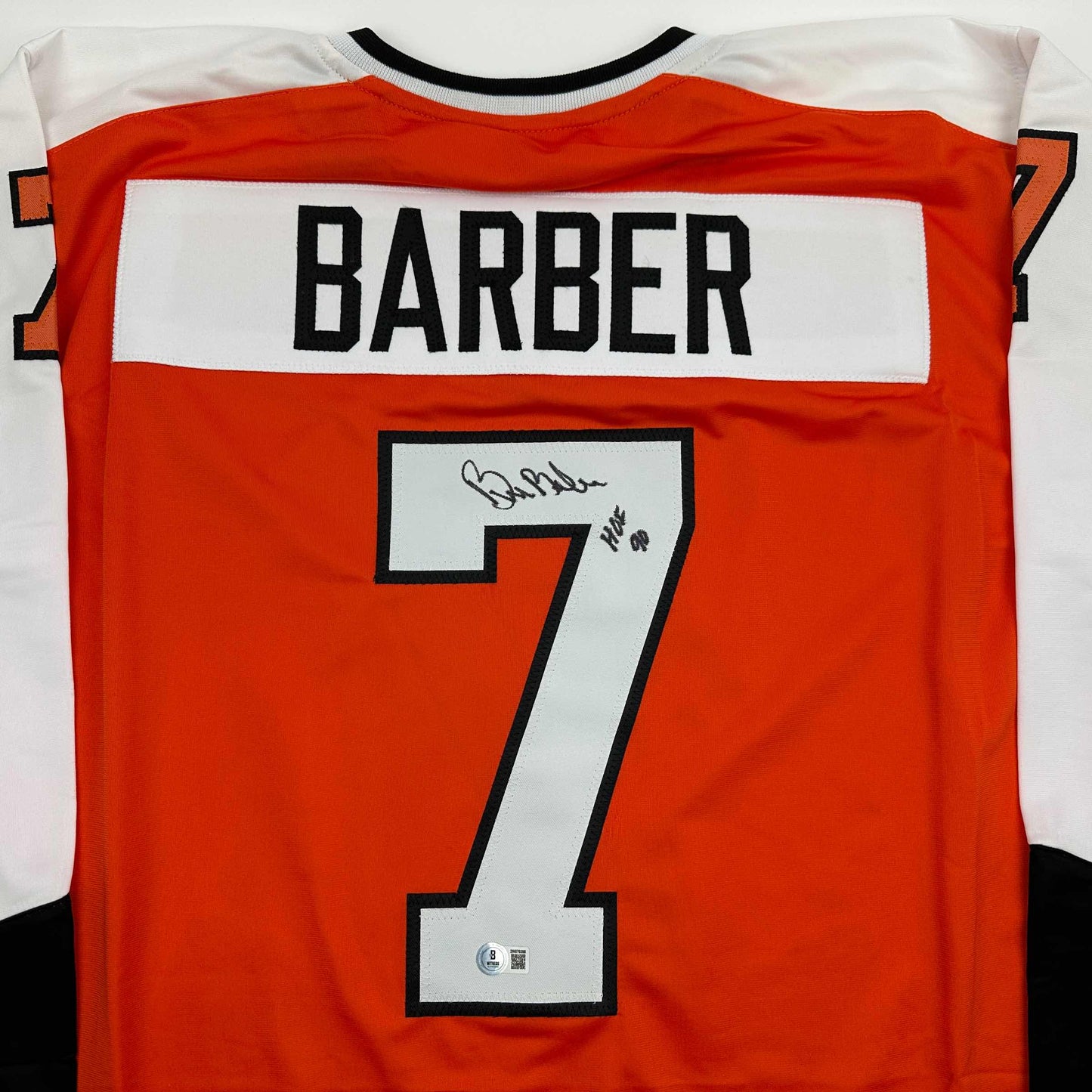 Back view of signed orange Philadelphia hockey jersey number 7 with "BARBER" nameplate and handwritten autograph.