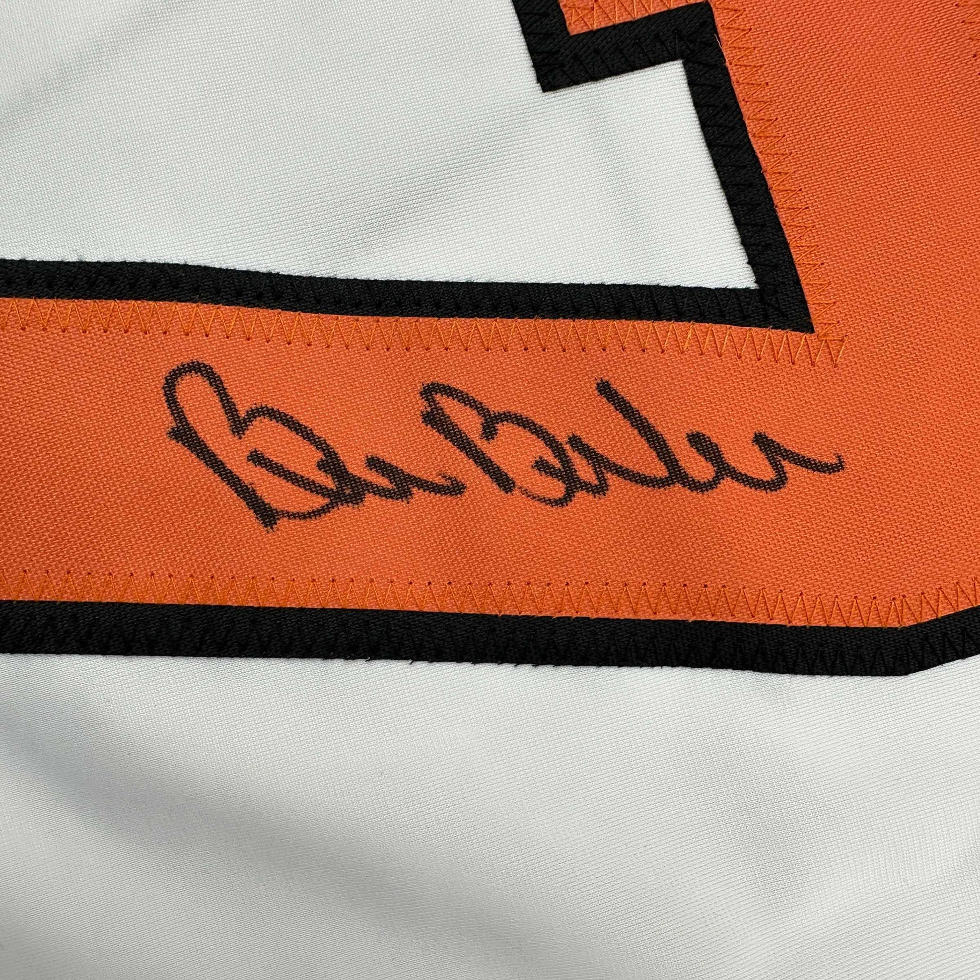 Close-up of handwritten signature on orange stripe of white hockey jersey with black trim.