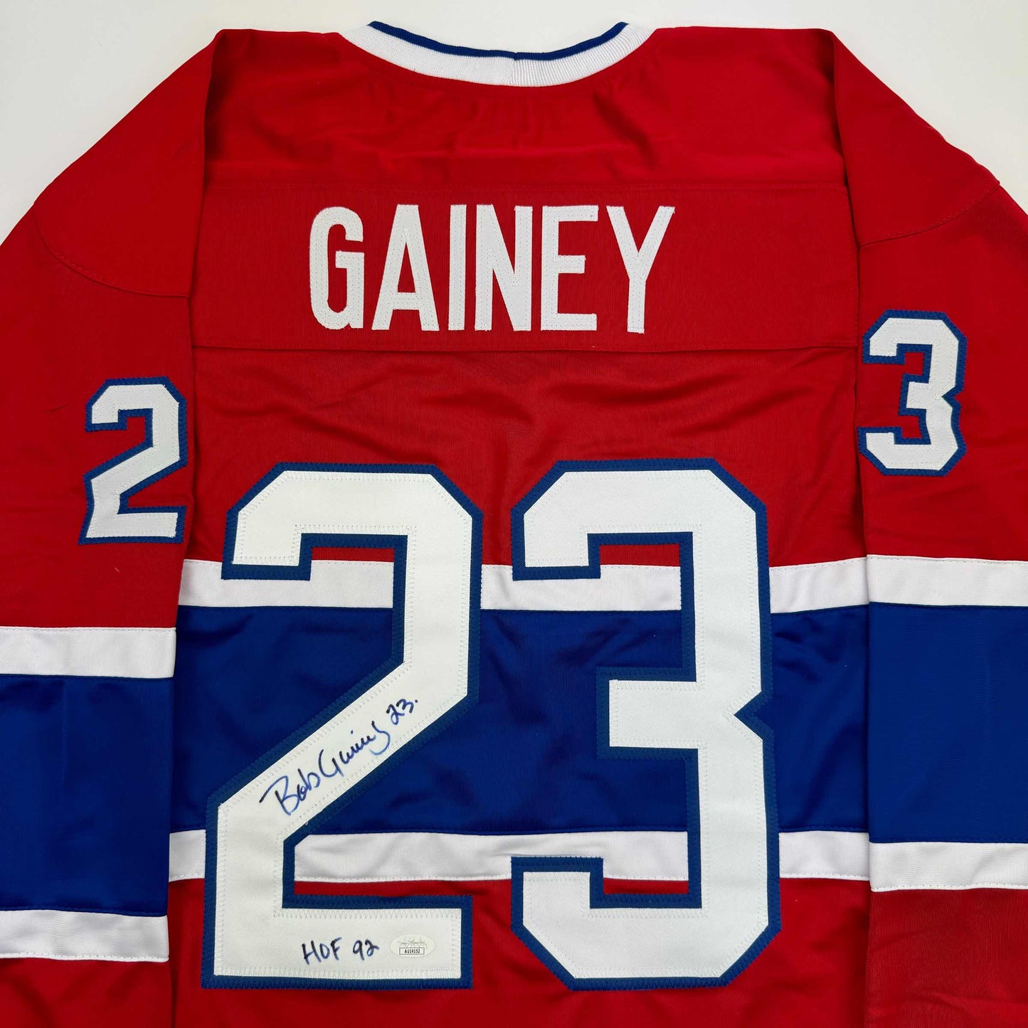 Back view of red, white and blue Montreal Canadiens hockey jersey number 23 with "GAINEY" nameplate and autographed inscription.