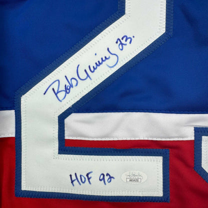 Close-up of white shoulder patch on blue hockey jersey showing handwritten "Bob Gainey '23" signature and "HOF 92" text.