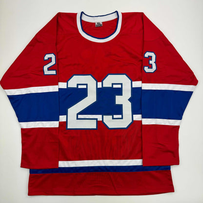 Flat lay of red, white, and blue Montreal hockey jersey with number 23 and shoulder numbers 2 and 3 visible.