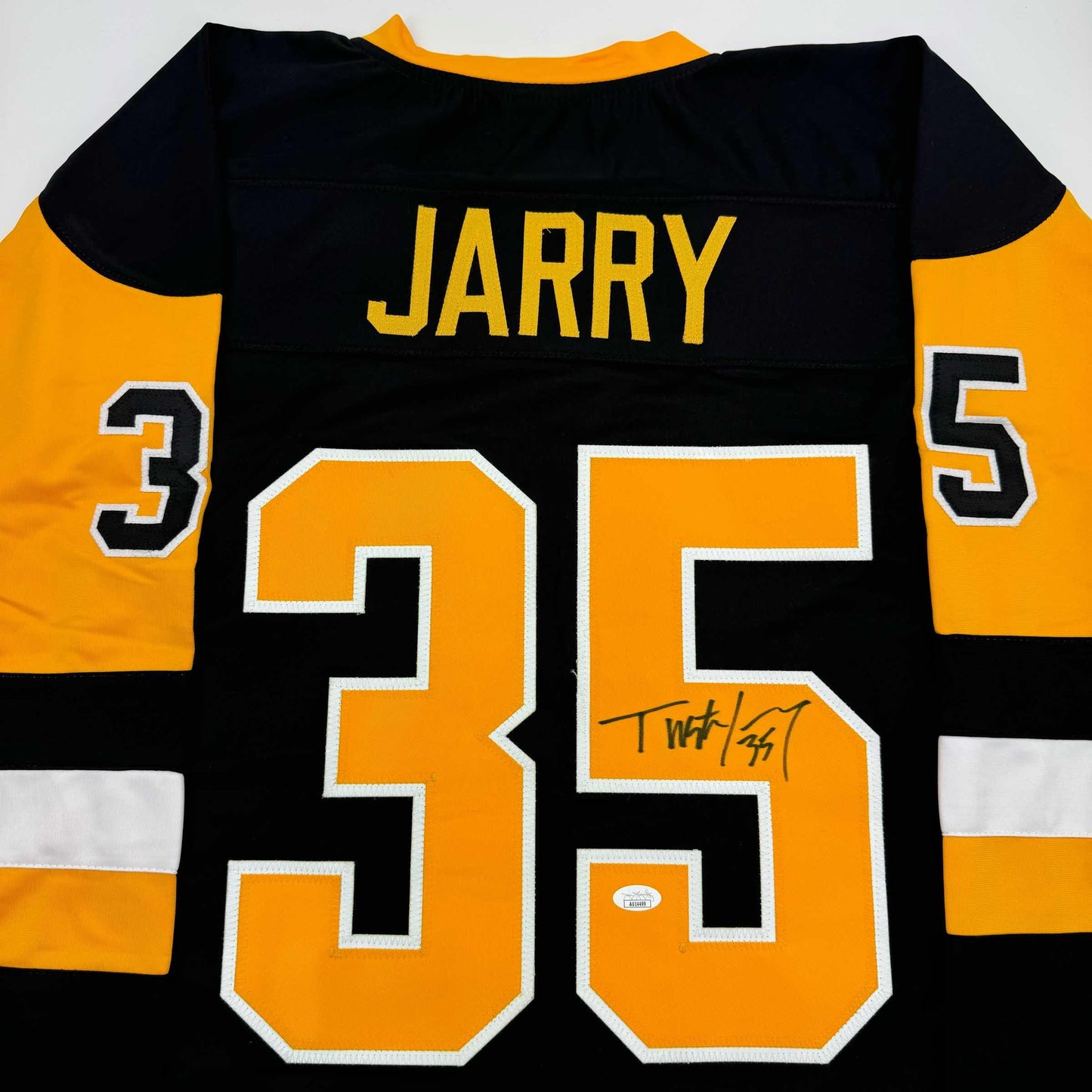 Back view of black and gold hockey jersey with "JARRY" and number 35 in orange with white trim, signed in black marker.