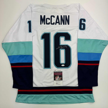 Rear view of white Jared McCann hockey jersey number 16 with teal and navy stripes, JSA authentication certificate visible.