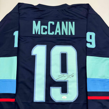 Back view of navy hockey jersey with "McCann" and number 19 in light blue, signed across the number 9.