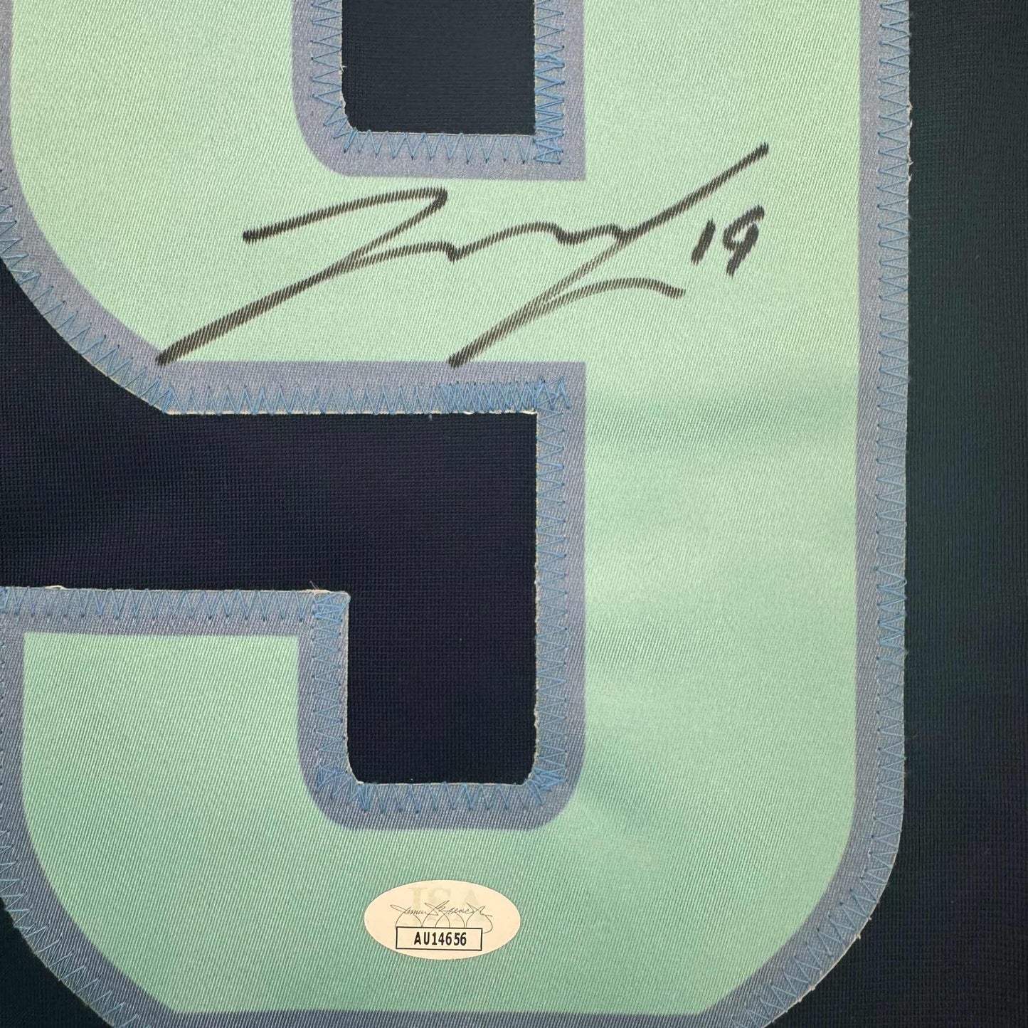 Close-up of mint green hockey jersey back showing black mesh panels, gray binding, handwritten signature, and JSA authentication label.