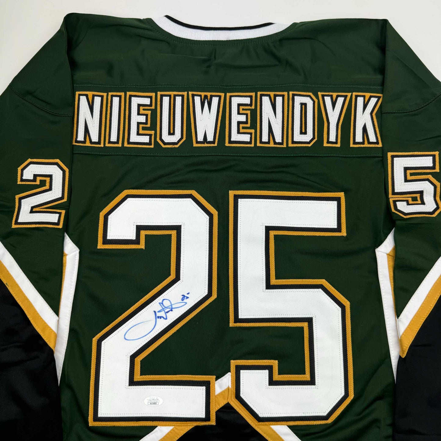 Back view of green hockey jersey with "NIEUWENDYK" and number 25 in white and gold lettering, autographed in blue ink.